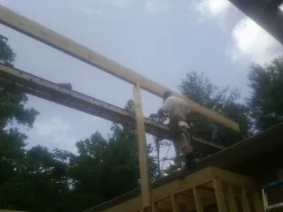 Carpenter setting a ridge beam over a new addition frame — Ice Dam Removal by Roofing Brothers in Island