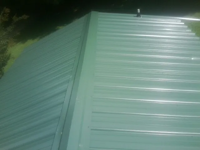New green metal panels meeting at the ridge of a roof — Flat Roof Repair work by our crew in Island