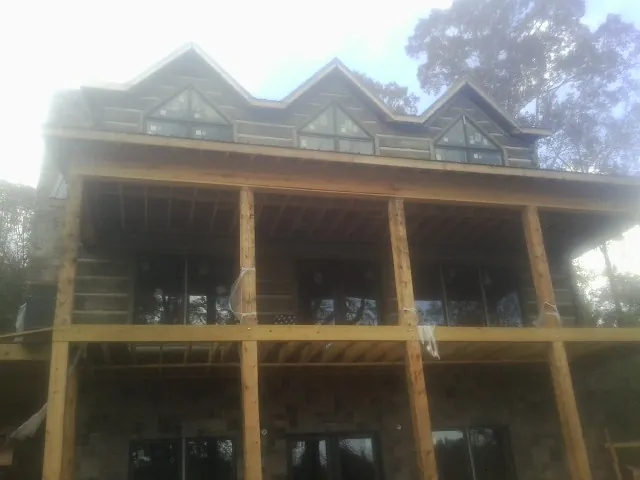 Dormers and porch framing on a large log home under construction — Roof Coating work by our crew in Island