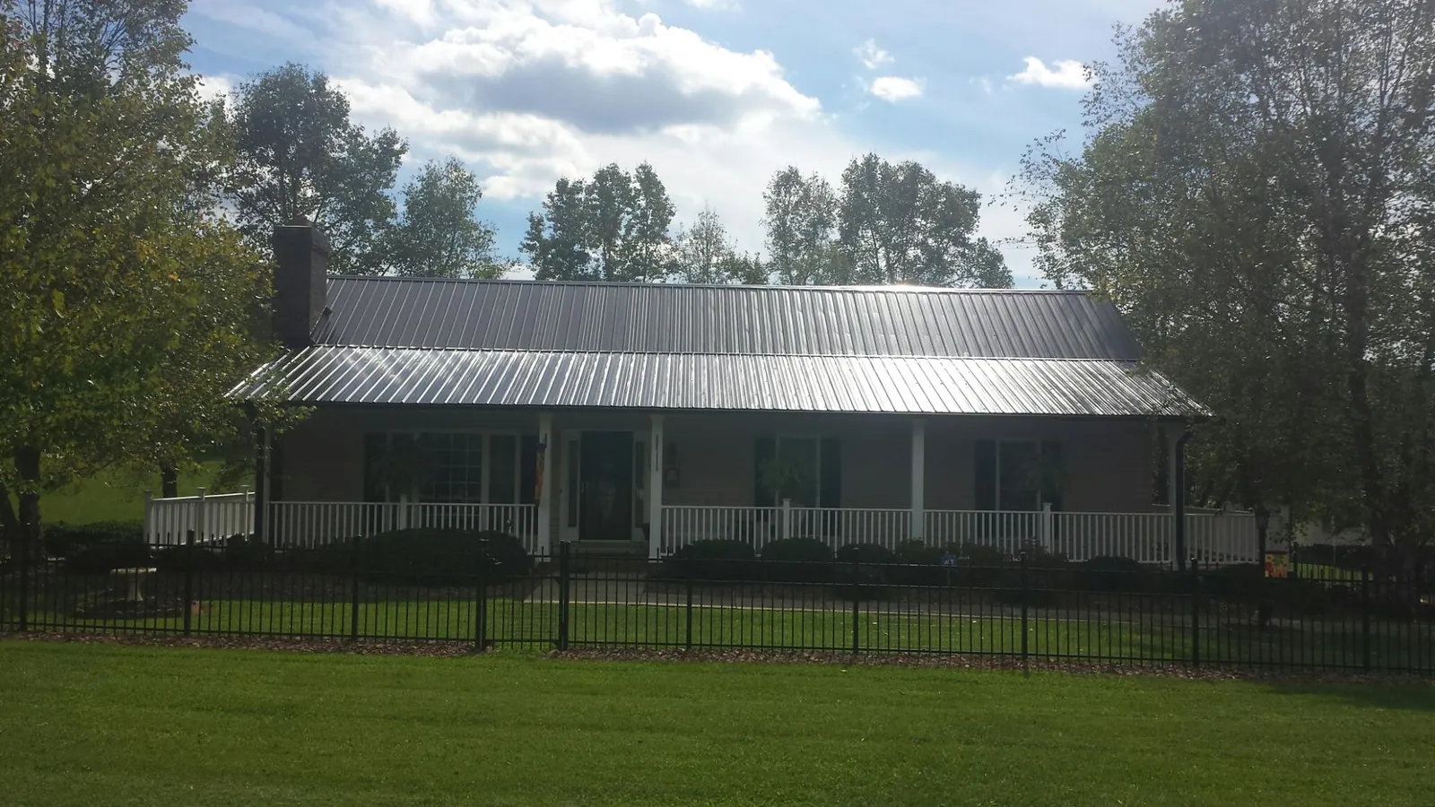 Gray metal roof on a brick ranch with a full width front porch — Gutter Guard Installation work by our crew in Island