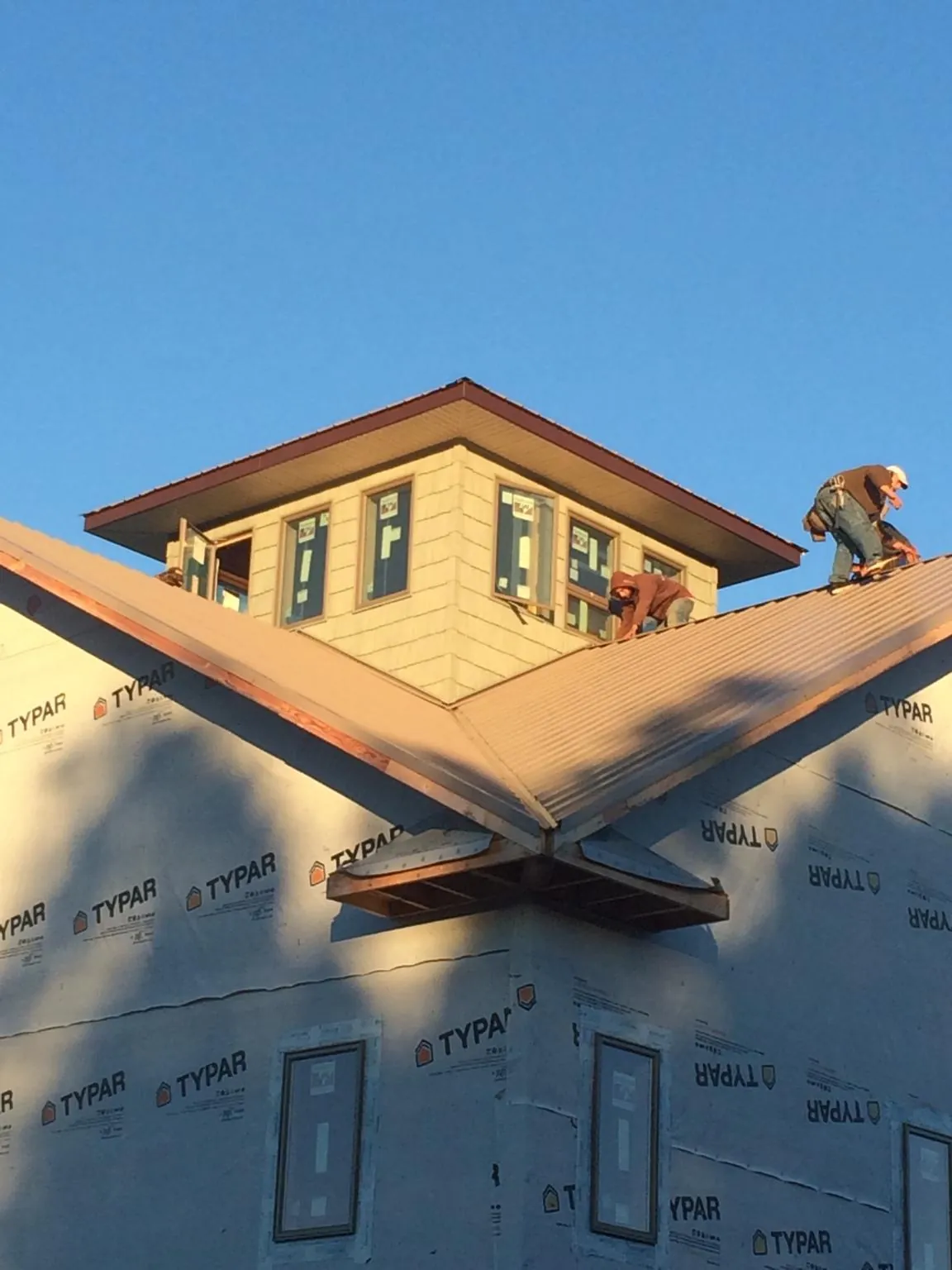 Roofers working around a rooftop cupola on a new metal roof at sunset — Roof Waterproofing in Island by Roofing Brothers